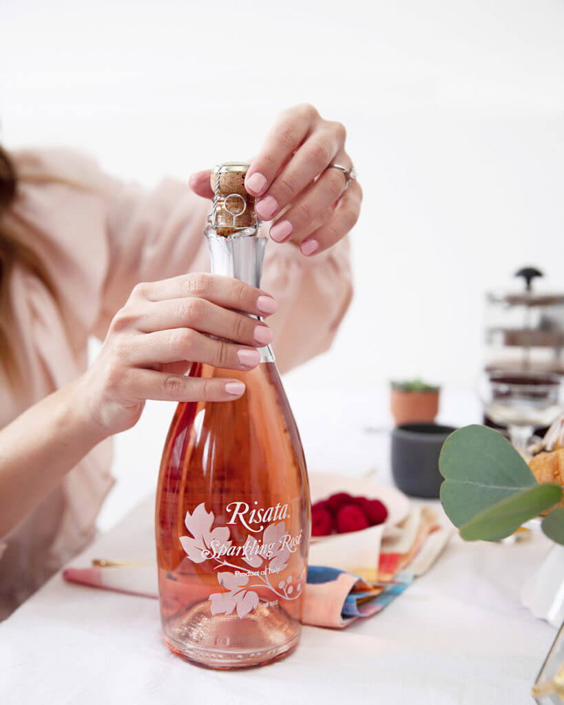 Women Opening a Risata Sparkling Rose Bottle