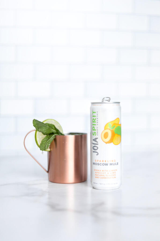 joia moscow mule can and a drink decorated with lemon and leaf
