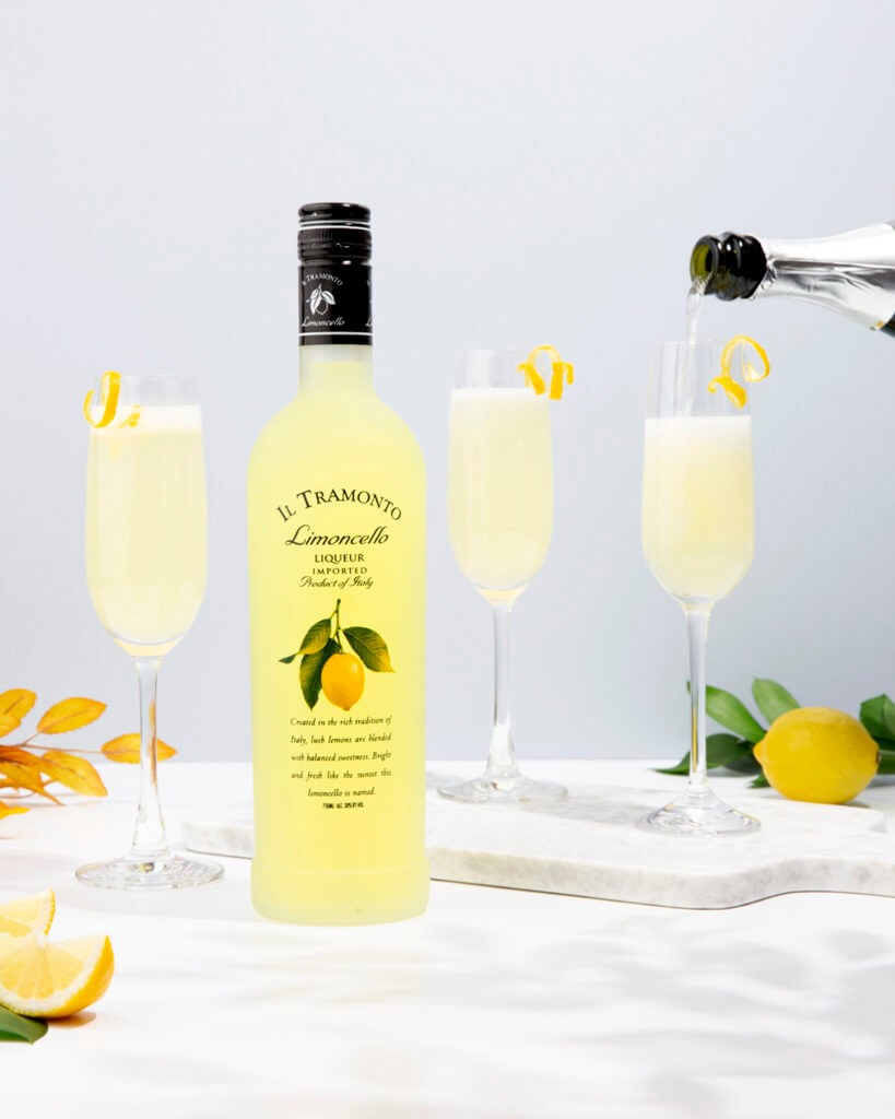 ILTramonto Limoncello Bottle with 3 drinks in the background decorated with slices of lemon