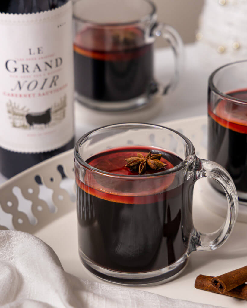 Mulled Wine Drink with an orange in it and a le grand noir bottle behind it